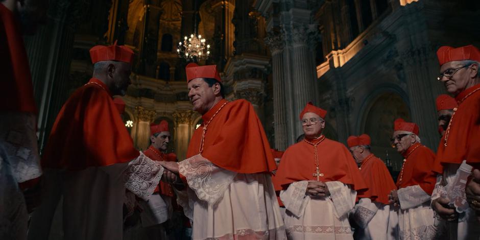 Cardinal Duretti shakes the hand of another cardinal before the election.