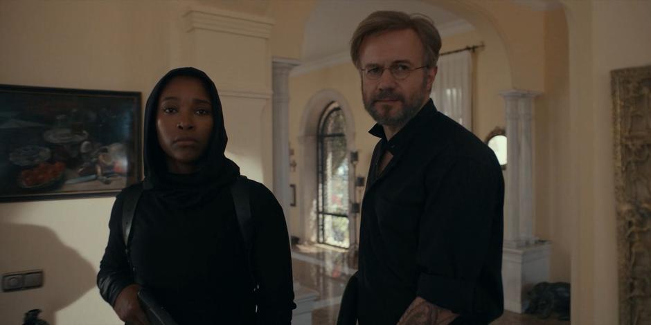 Mary and Father Vincent turn when they see the villa's owner painting outside.