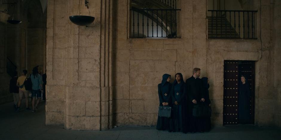 Beatrice, Mary, Father Vincent, and Camila lean against the wall waiting as Ava opens the door from the other side.