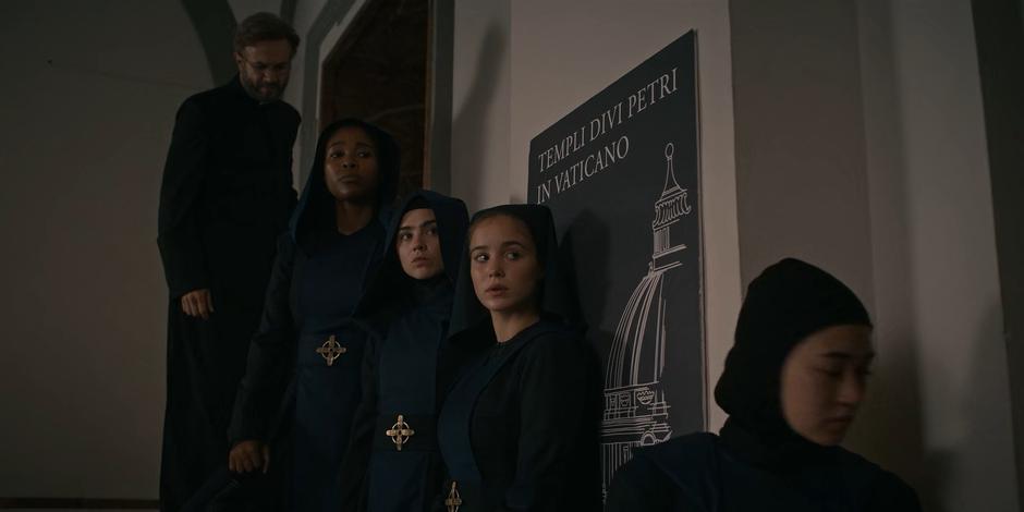 Father Vincent, Mary, Camila, and Ava wait as Beatrice takes care of the camera.