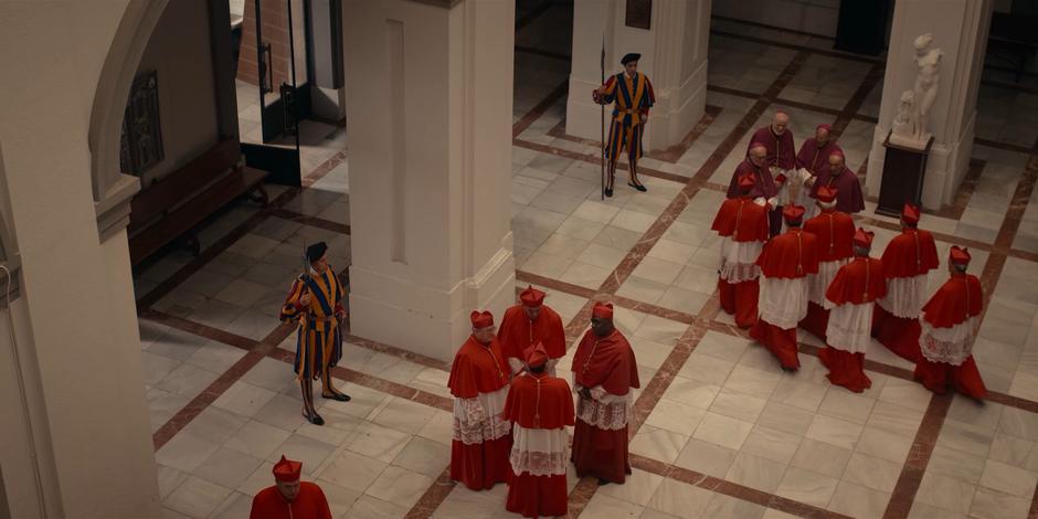 Several groups of cardinals chat in the courtyard.