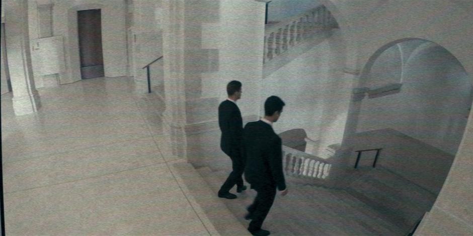 A security camera shows two guards patrolling down the stairs.