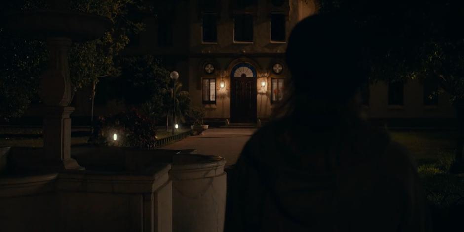 Ava approaches the front of the orphanage at night.