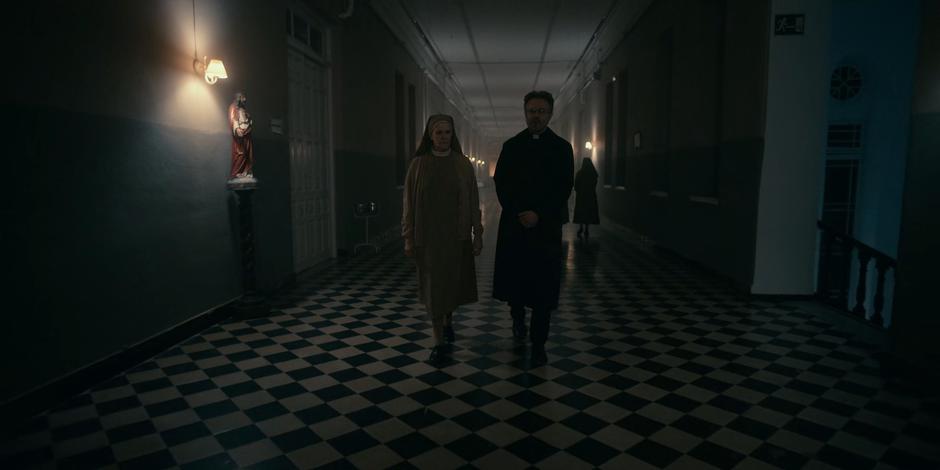 Sister Frances walks down the hallway with Father Vincent telling him about Ava.