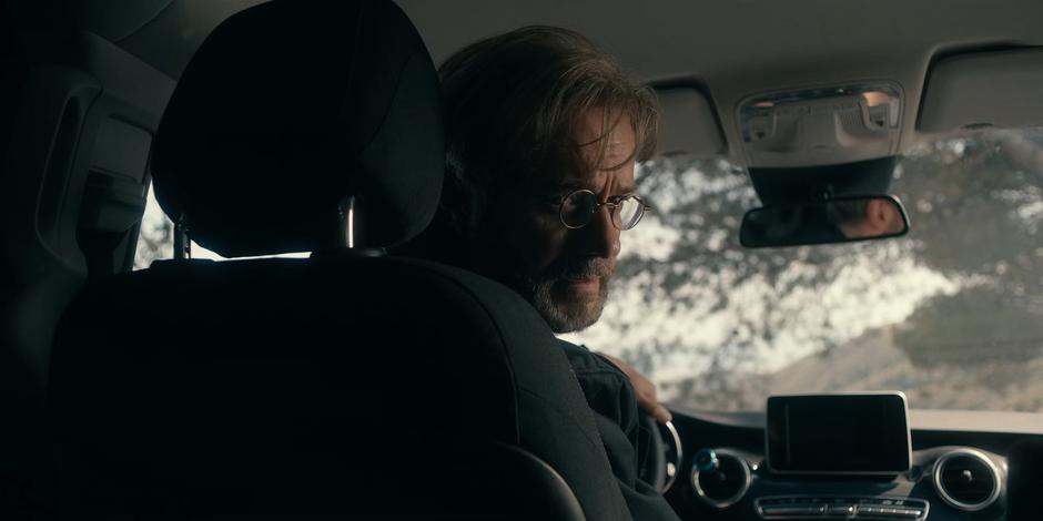 Father Vincent looks back over his shoulder from the driver's seat.