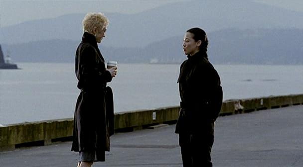 Madame X and Brin talk on the pier.