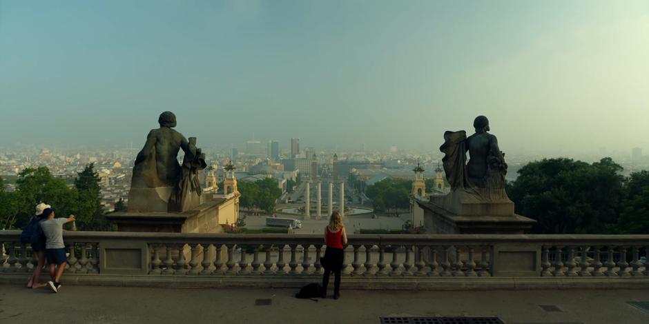 Henry takes off her jacket as she looks out over the city.