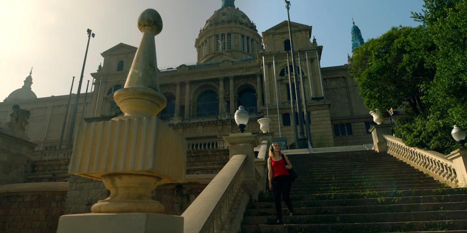 Henry walks down the steps in front of the museum while listening to music.