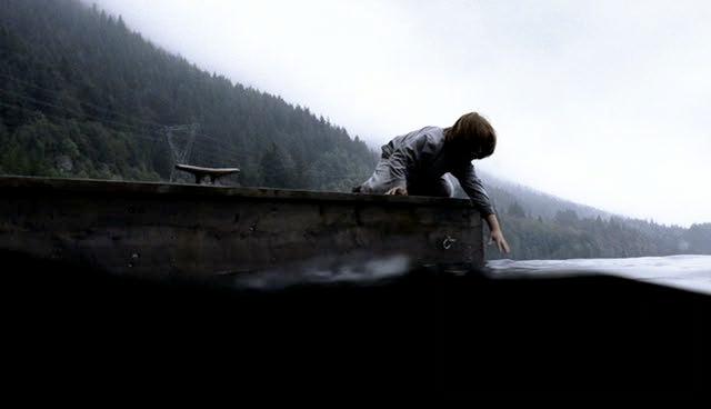 Lucas Barr leans off the dock towards the lake surface.