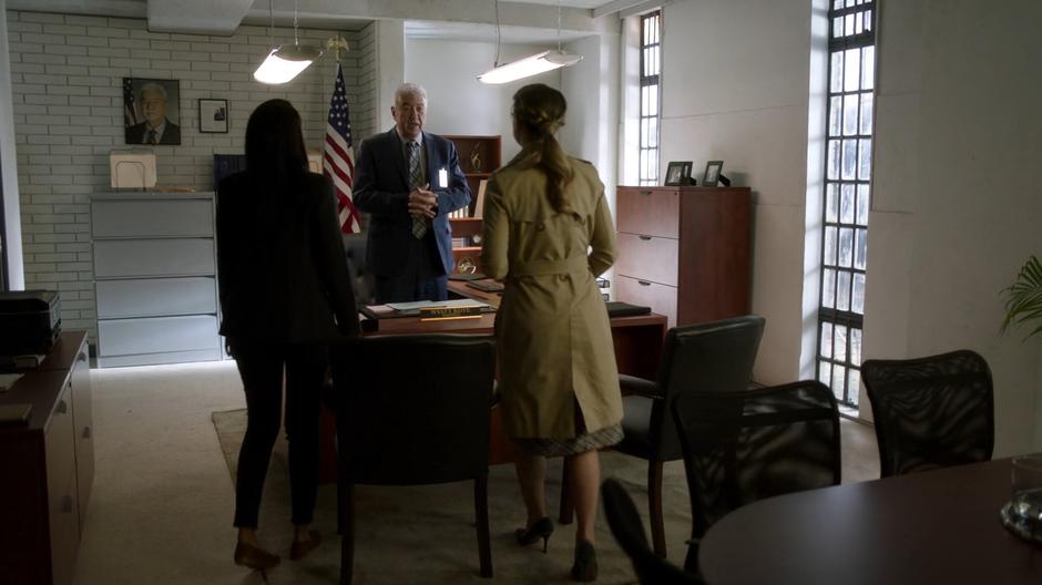 Warden Kote welcomes Kelly and Kara to his office.