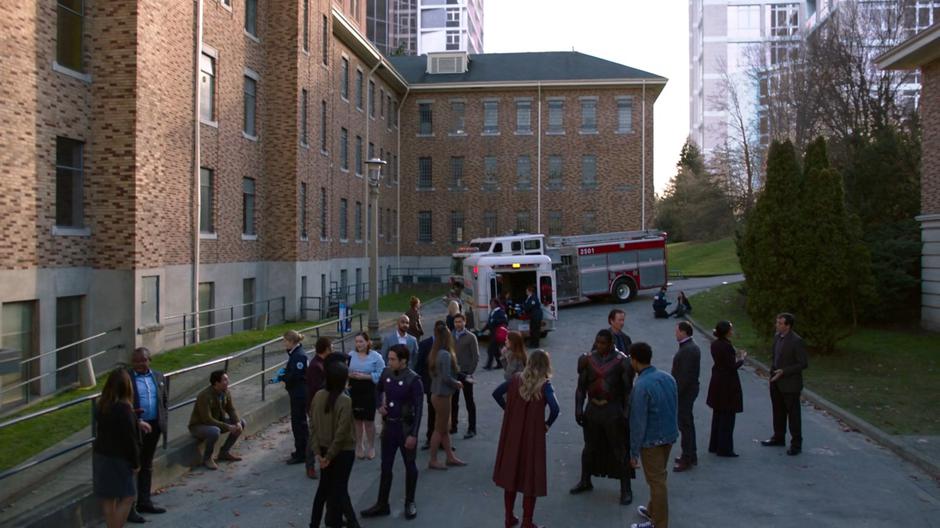 The Superfriends and the people in the building for the vote gather in the drive after the incident.