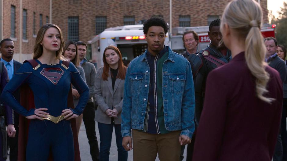 Kara, Orlando, J'onn, and other bystanders watch as Councilwoman Rankin informs them of the vote.