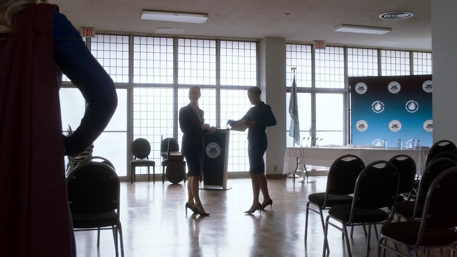 Councilwoman Rankin turns from talking to her aid as Kara appears as Supergirl.