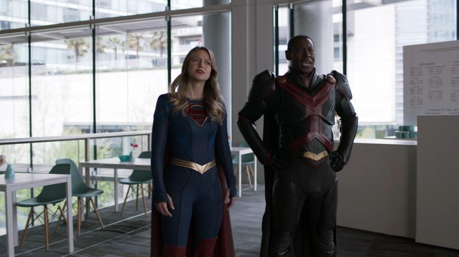 J'onn cheers on Alex while Kara looks on with concern.