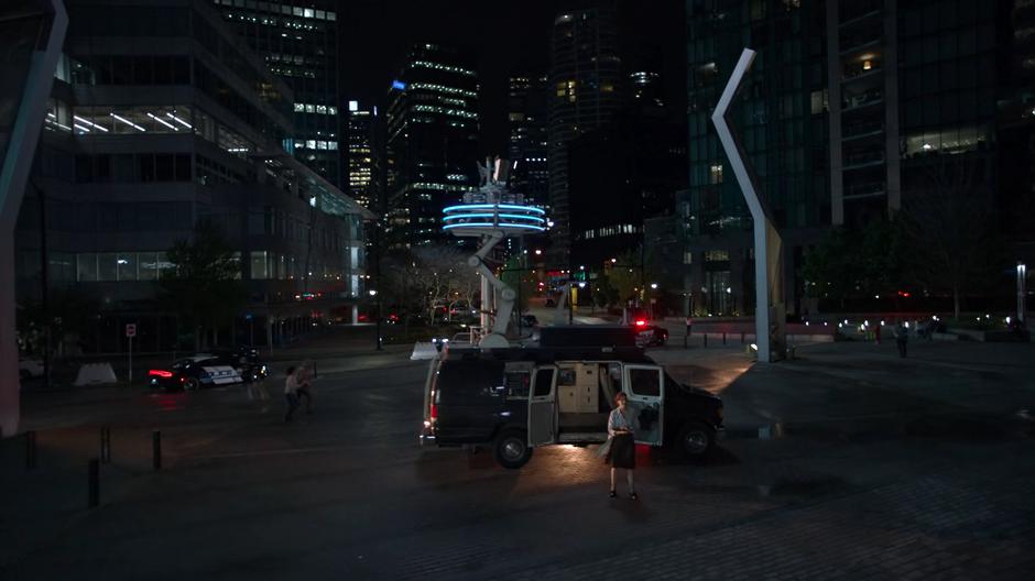 Dr. Lahr stands in fron of the van holding her lightning machine and watches the storm gathering.