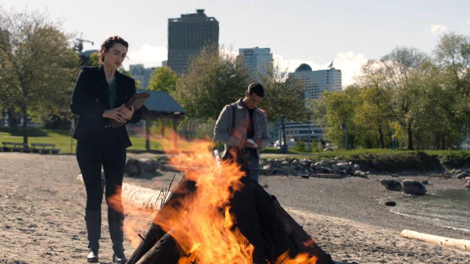 Lena casts the spell over the bonfire while William takes notes.