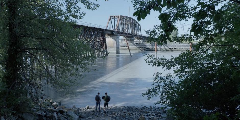 Two people discover the Mat Hatter's hat at the edge of the river.