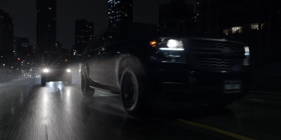 The two mercenary vehicles races across the bridge in the dark.