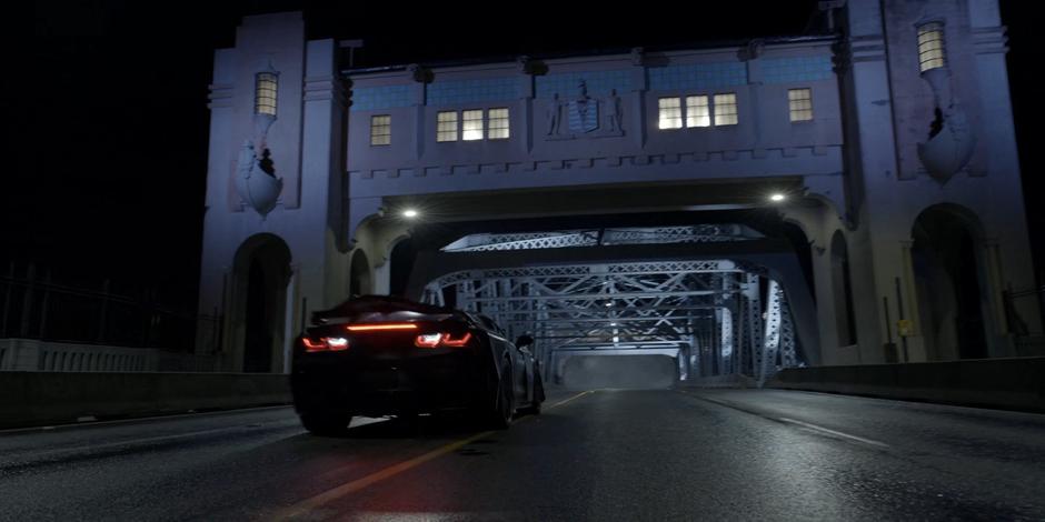 The Batmobile comes to a stop as the smoke from the explosion fills the far end of the bridge.