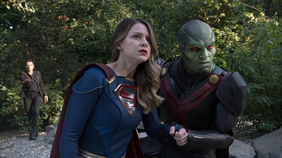 J'onn helps Kara stand as they watch Lex and Nyxly fight it out while behind them Lena raises her hand to use her magic.