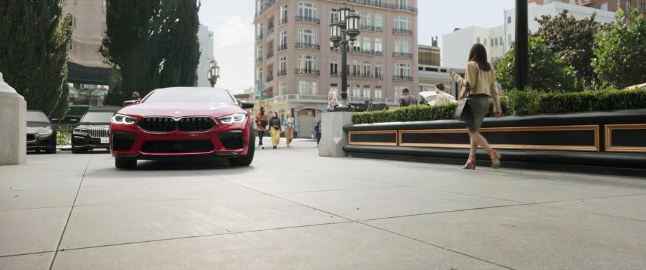 A fancy red car pulls up in front of the hotel.