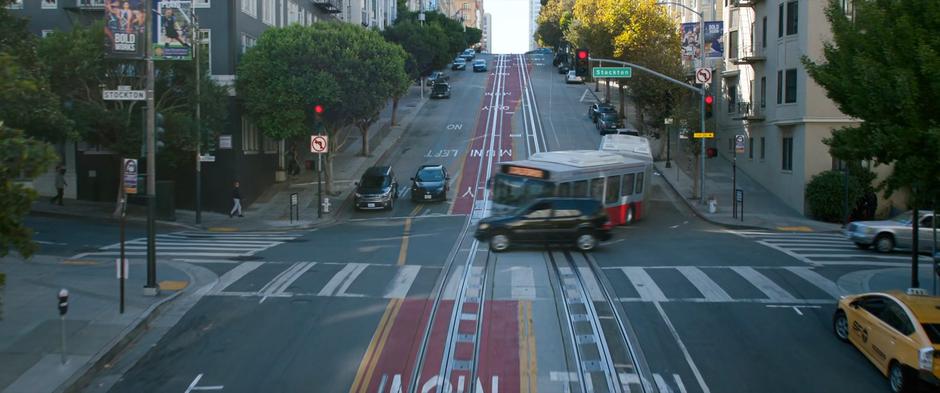 The bus turns the corner and barely misses hitting a car.