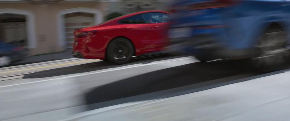 The red car races up the hill on the streetcar tracks.