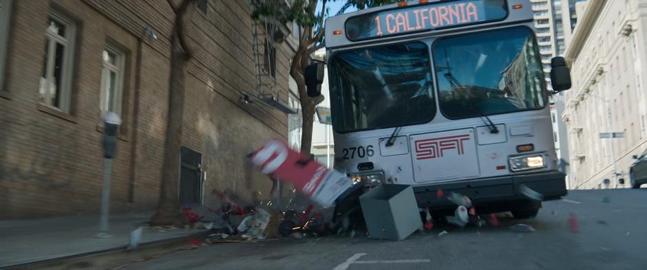 Debris flies all around the front of the bus as it plows through a scooter parking spot.