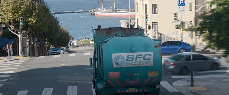 A SFC Sanitation truck drives slowly downhill of the runaway bus.