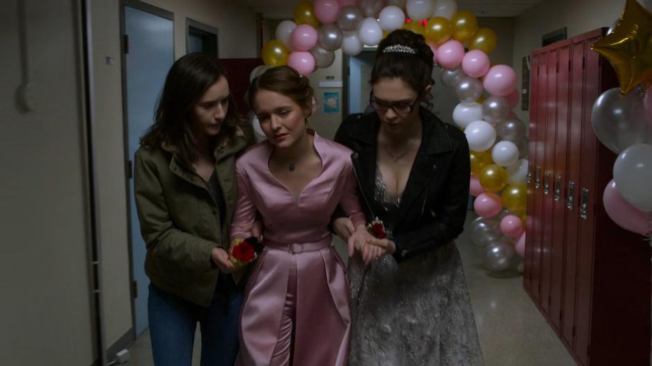 Young Alex and Nia help an injured Kara down the hallway.