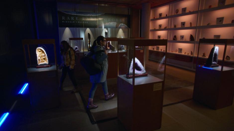 Young Kara and Nia search the room for the Dysprosium geode.