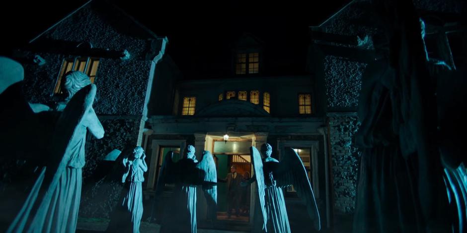 Professor Jericho and the Doctor look through the front door to where a group of Weeping Angels are waiting.
