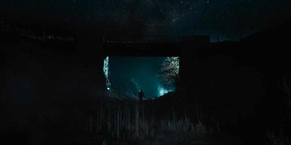 Vinder walks beneath a ruined bridge towards his ship.