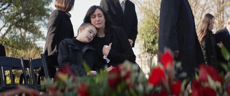 Young Kate and Eleanor lean against one another at the graveside while other mourners walk away.