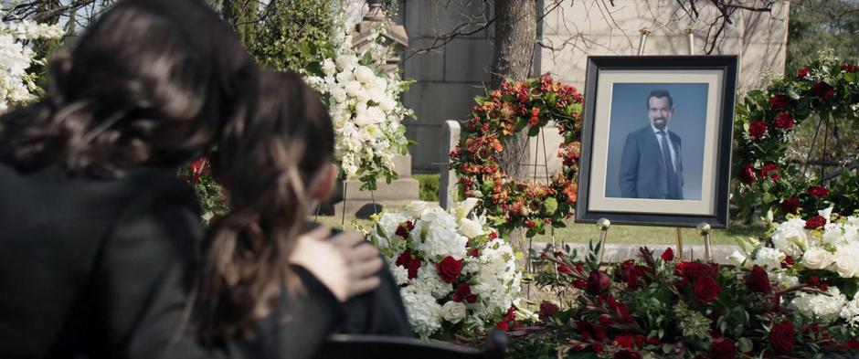 Eleanor and young Kate lean against one another while looking at the photo of Derek Bishop over the grave.