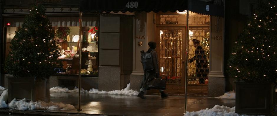 The doorman opens the door for Kate as the approaches on the snowy street.