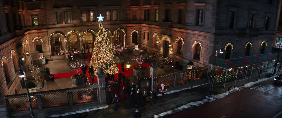 Establishing shot of the hotel courtyard with a Christmas tree as people stream in for the gala.