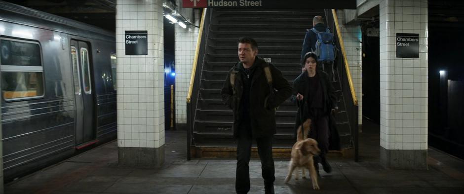 Kate follows Clint into the subway while holding Pizza Dog's leash.