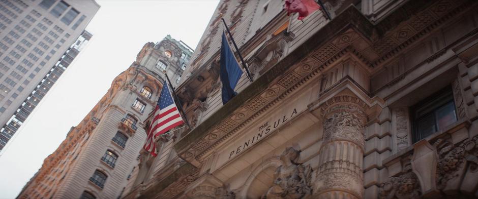 Establishing shot of the hotel's sign with several flags waving above.