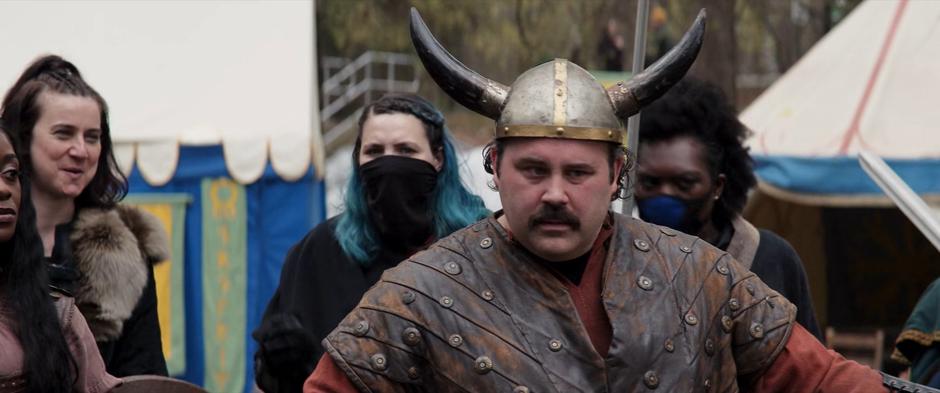 A man in a viking helmet and others watch the battle.
