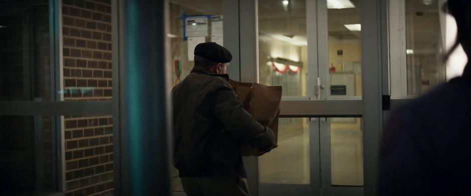 Kate approaches a man entering the building with several bags of groceries and offers to help.