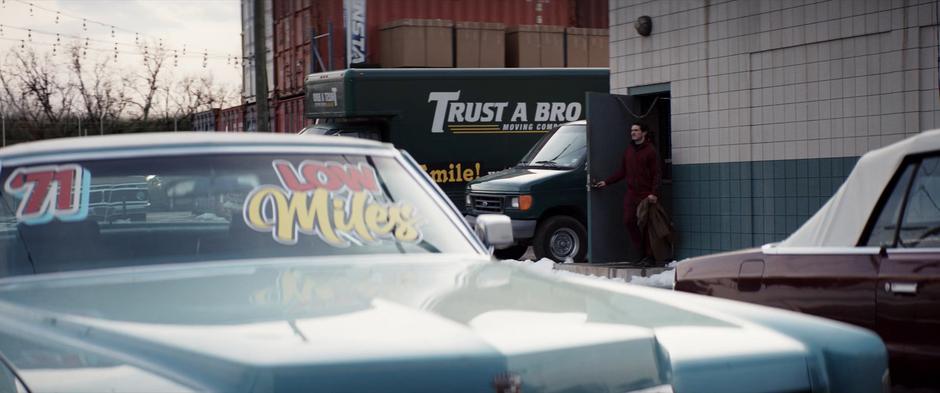 Kazi exits a building on the used car lot.