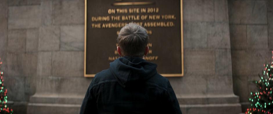 Clint stares up at the plaque memorializing the Battle of New York while talking to Natasha.