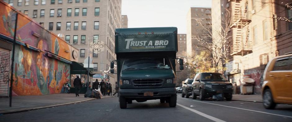 The Trust a Bro Moving Company truck drives down the street.