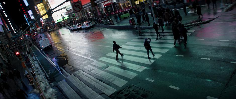 Clint walks across the street in Times Square at night.