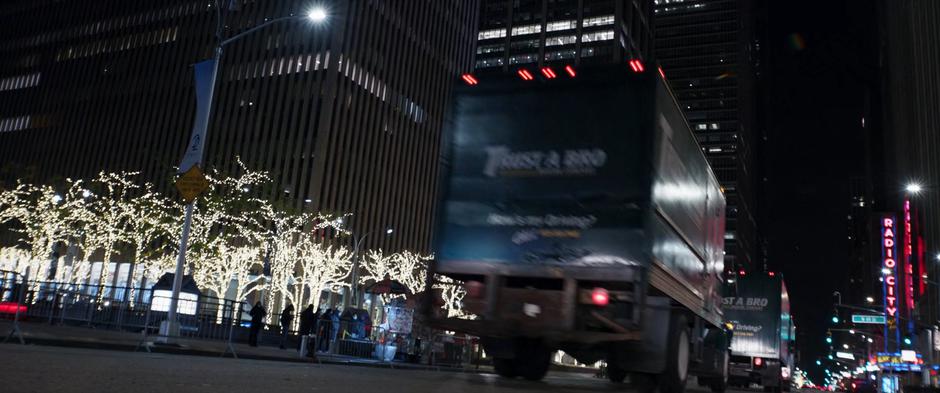 Trust a Bro Moving Company trucks drive downt he road towards Rockefeller Plaza.