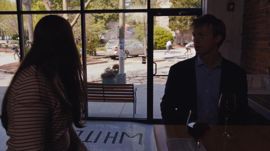 Two people turn towards the window as the strange battle occurs outside.