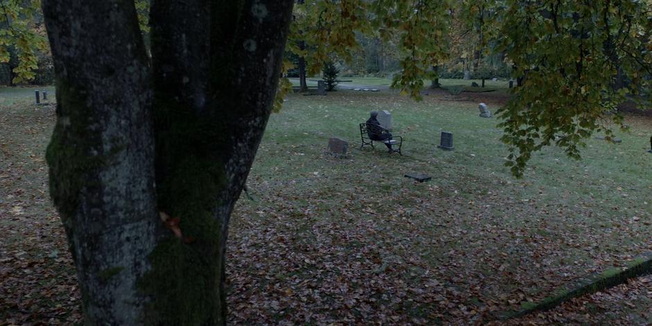 Ryan sits on a bench in front of her mother Cora's gravestone.