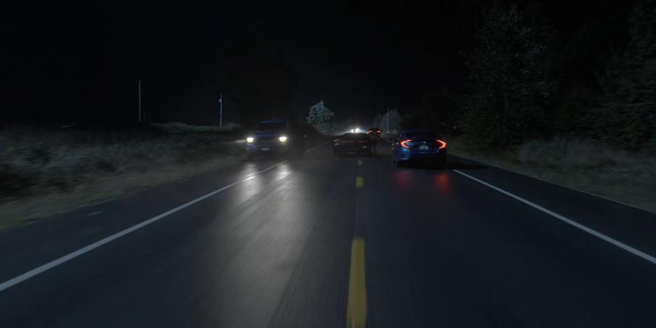 The Batmobile weaves through traffic as it races down the road.