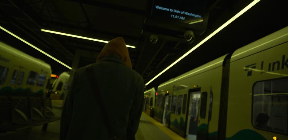 Angela walks across the light rail platform towards the exit.